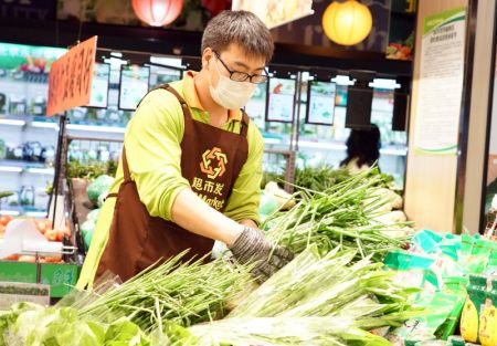 (miniature) Un employé dispose des légumes sur l'étal d'un supermarché de l'arrondissement de Haidian à Beijing