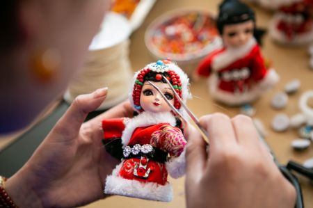 (miniature) Un membre d'une coopérative d'artisanat fabrique une poupée porte-bonheur dans la communauté de Baihe du village de Tangke dans le district de Ruoergai