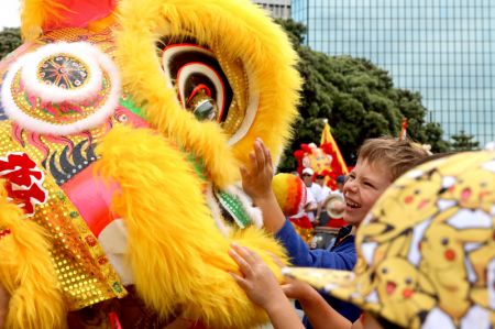 (miniature) Un enfant essaie de toucher les accessoires de la danse du lion lors d'un défilé du Nouvel An chinois à Wellington