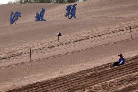 (miniature) Un touriste sur un toboggan de sable dans le site touristique de Shapotou