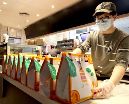 (miniature) Un employé prépare des commandes en ligne dans une boutique Burger King à Shanghai