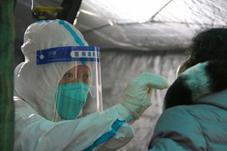 (miniature) Un travailleur médical prend un échantillon de gorge sur une personne pour le test d'acide nucléique de la COVID-19 dans un site de test dans l'arrondissement de Fengtai à Beijing