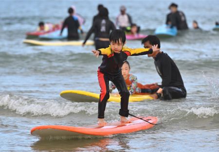 (miniature) Un enfant surfe dans la baie Riyue