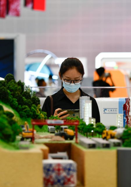 (miniature) Une visiteuse regarde une maquette lors de la Conférence sur la science du bâtiment et l'Exposition du bâtiment intelligent et écologique de Chine