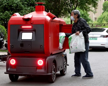 (miniature) Un habitant collecte des produits dans un véhicule de livraison sans pilote dans un quartier résidentiel à Shanghai