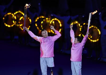 (miniature) Zheng Xiongying (à droite) et Hou Bin passent le flambeau lors de la cérémonie d'ouverture des 4es Jeux paralympiques asiatiques