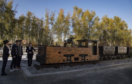 (miniature) Des touristes contemplent une vieille locomotive autrefois utilisée pour transporter le charbon dans le parc industriel culturel de Zhongneng
