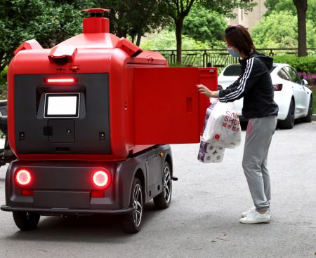 (miniature) Une habitante collecte des produits dans un véhicule de livraison sans pilote dans un quartier résidentiel à Shanghai
