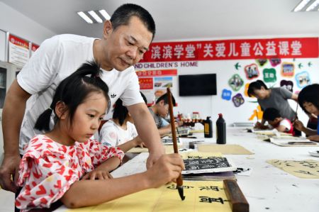 (miniature) Un enseignant de bien-être public donne des instructions aux enfants pour la pratique de la calligraphie chinoise au bourg de Huji