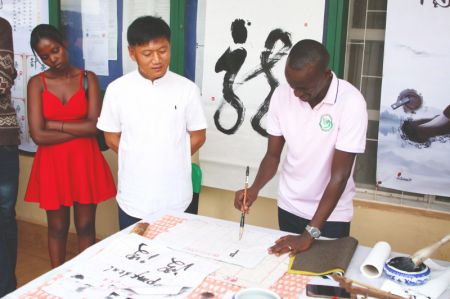(miniature) Un homme s'essaie à la calligraphie chinoise lors d'une exposition culturelle chinoise à Kigali