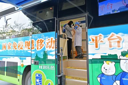 (miniature) Une employée de santé examine une femme qui vient d'être vaccinée dans un véhicule mobile de vaccination contre le COVID-19 près du quartier des affaires de Xidan