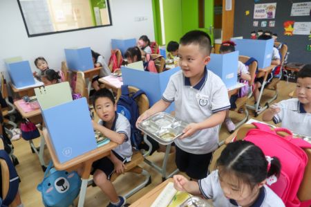 (miniature) Un élève retourne son assiette vide après le déjeuner dans une école primaire de l'arrondissement de Changning à Shanghai