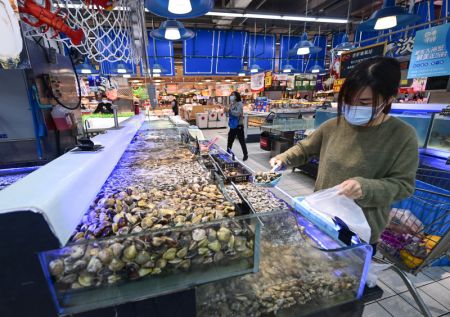 (miniature) Une habitante achète des fruits de mer dans un supermarché de l'arrondissement de Jiading