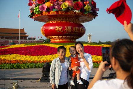 (miniature) Des touristes posent pour une photo devant un panier de fleurs sur la place Tian'anmen à Beijing