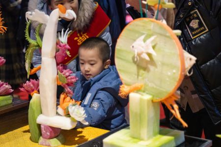(miniature) Un petit garçon regarde des sculptures réalisées à partir de légumes et de fruits lors d'un festival gastronomique à Harbin
