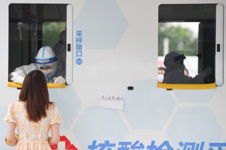 (miniature) Un professionnel de santé effectue un prélèvement de gorge sur une femme dans un véhicule de dépistage mobile récemment mis en service dans l'arrondissement de Xicheng