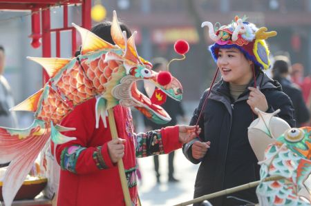 (miniature) Une touriste achète un chapeau en forme de dragon lors d'une foire à Shangqiu