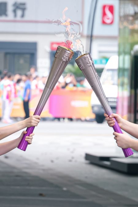 (miniature) Des porteurs de la torche se passent la flamme lors du relais de la torche des 19e Jeux asiatiques à Hangzhou