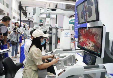 (miniature) Des visiteurs essaient un robot chirurgical lors de la Conférence mondiale sur la robotique 2023