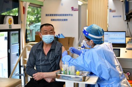 (miniature) Un homme reçoit une dose de vaccin dans un véhicule mobile de vaccination contre le COVID-19 près du quartier des affaires de Xidan