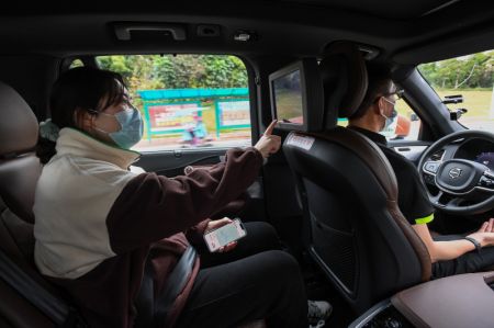 (miniature) Une cliente (à gauche) utilise l'écran d'un véhicule à conduite autonome de Didi alors qu'un technicien vérifie le trajet du véhicule sans toucher au volant dans l'arrondissement de Huadu