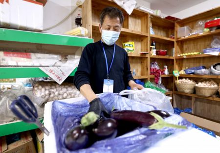 (miniature) Un employé emballe des légumes pour des commandes en ligne dans un supermarché à Shanghai