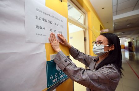 (miniature) Une membre du personnel affiche des informations concernant la salle d'examen dans un site d'examen national d'entrée à l'université