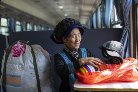 (miniature) Une femme de l'ethnie Yi organise les produits qu'elle a achetés dans la ville de Xichang à bord du train 5634 dans la province du Sichuan (sud-ouest de la Chine)