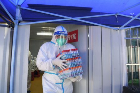 (miniature) Un professionnel de santé transporte des échantillons d'acide nucléique dans un laboratoire de dépistage à Sanya