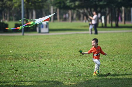 (miniature) Un enfant s'amuse avec un cerf-volant au parc Evergreen de Haikou