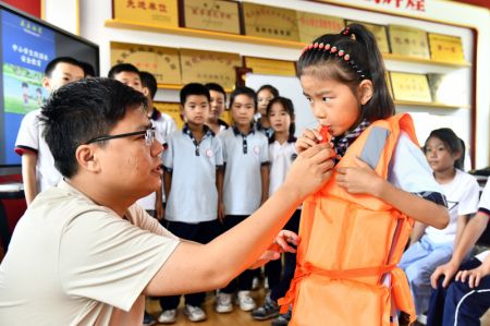 (miniature) Des enfants regardent un enseignant de bien-être public apprendre à une fille la façon d'utiliser un gilet de sauvetage au bourg de Shimiao