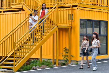 (miniature) De jeunes touristes devant des bâtiments colorés construits à base de conteneurs reconvertis dans le village de Beilian