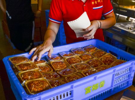 (miniature) Un membre du personnel vérifie des gâteaux de lune dans un magasin de gâteaux de lune à la mode de Hainan