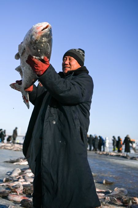(miniature) Un pêcheur montre un grand poisson fraîchement capturé sur le lac Chagan à Songyuan
