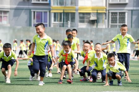 (miniature) Des écoliers suivent un cours d'éducation physique sur le terrain de jeu d'une école primaire à Renhuai