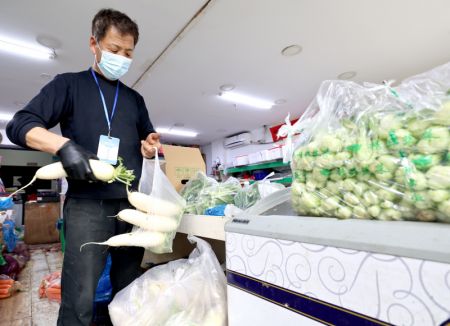 (miniature) Un employé emballe des légumes pour des commandes en ligne dans un supermarché à Shanghai