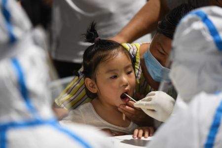 (miniature) Un membre du personnel médical prélève un échantillon de gorge sur une fille pour des tests d'acide nucléique