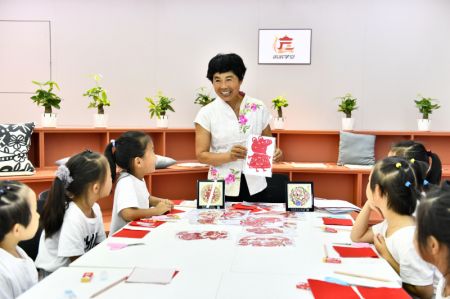 (miniature) Une enseignante de bien-être public donne aux enfants un cours de découpage de papier au bourg de Jianglou