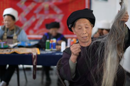 (miniature) Une brodeuse de l'ethnie Shui fabrique des fils de couture pour la broderie traditionnelle en fils de queue de cheval avec des fibres de queue de cheval et des fils de soie dans la communauté de relogement Xuehuahu du bourg de Zhonghe