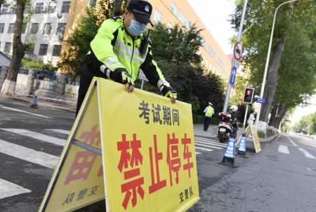 (miniature) Un agent de la circulation installe un panneau indiquant stationnement interdit à l'extérieur d'un site d'examen d'un lycée de Changchun
