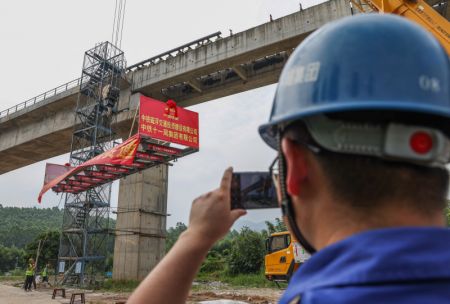(miniature) Un ouvrier prend des photos pendant la pose du dernier rail de 10 mètres de long sur le chantier d'une ligne maglev à moyenne et basse vitesse dans la ville de Qingyuan