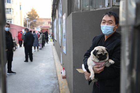 (miniature) Un homme porte son chien en attendant de passer un test d'acide nucléique dans un site de dépistage à Xi'an