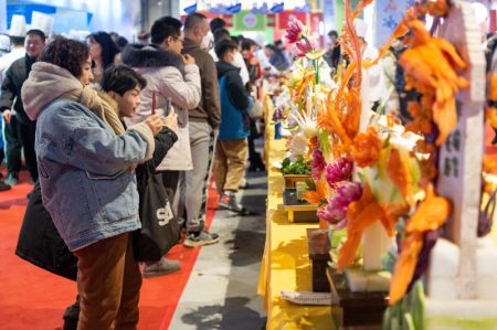 (miniature) Des touristes prennent des photos de sculptures réalisées à partir de légumes et de fruits lors d'un festival gastronomique à Harbin