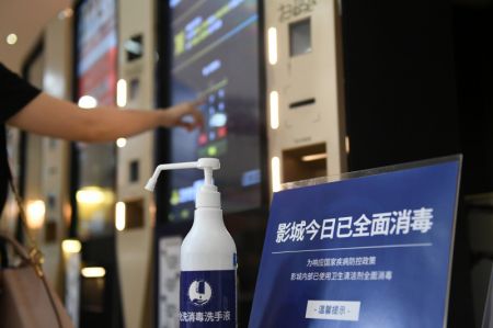 (miniature) Une bouteille de désinfectant pour les mains à côté d'un distributeur de tickets dans un cinéma de Tianjin