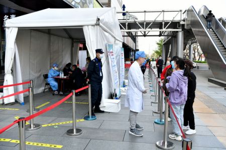 (miniature) Des habitants s'informent sur la vaccination contre le COVID-19 dans une installation mobile de vaccination près du quartier des affaires de Xidan