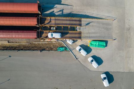 (miniature) Photo aérienne prise par drone de membres du personnel chargeant des véhicules à bord d'un train de fret JSQ à la gare du centre international de conteneurs de Harbin