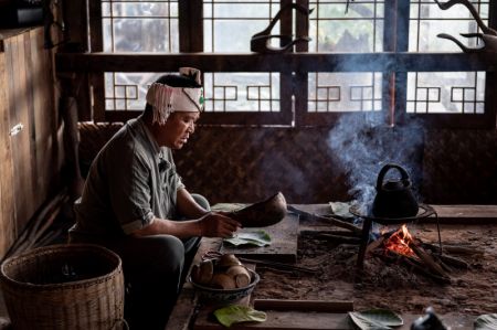 (miniature) Un cultivateur de thé fait cuire du thé sur la cheminée dans un village de la montagne Jingmai