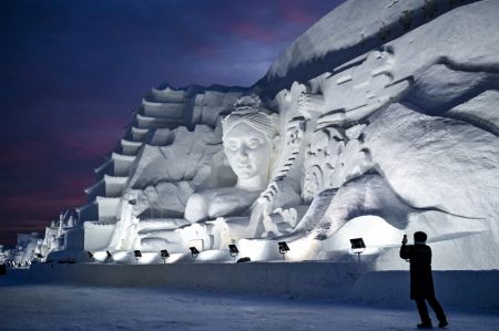 (miniature) Un touriste prend des photos d'une grande sculpture sur neige au Nouveau Monde de glace et de neige de Changchun