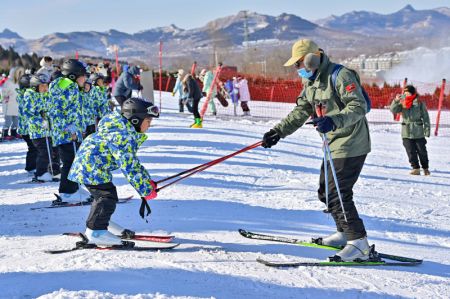(miniature) Un moniteur apprend à un enfant à faire du ski dans une station de sports d'hiver à Qingzhou