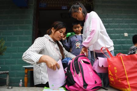 (miniature) Une femme aide sa fille à faire son sac d'école à Heping
